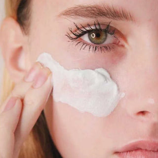 Model applying Dr. Lara Devgan Microdermabrasion Scrub to the cheek