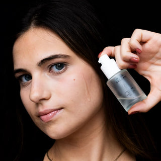 Model holding a Dr. Lara Devgan serum with dropper