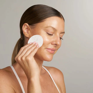 Model sweeping a ( plated ) Exosome Enhancer prep pad over the face